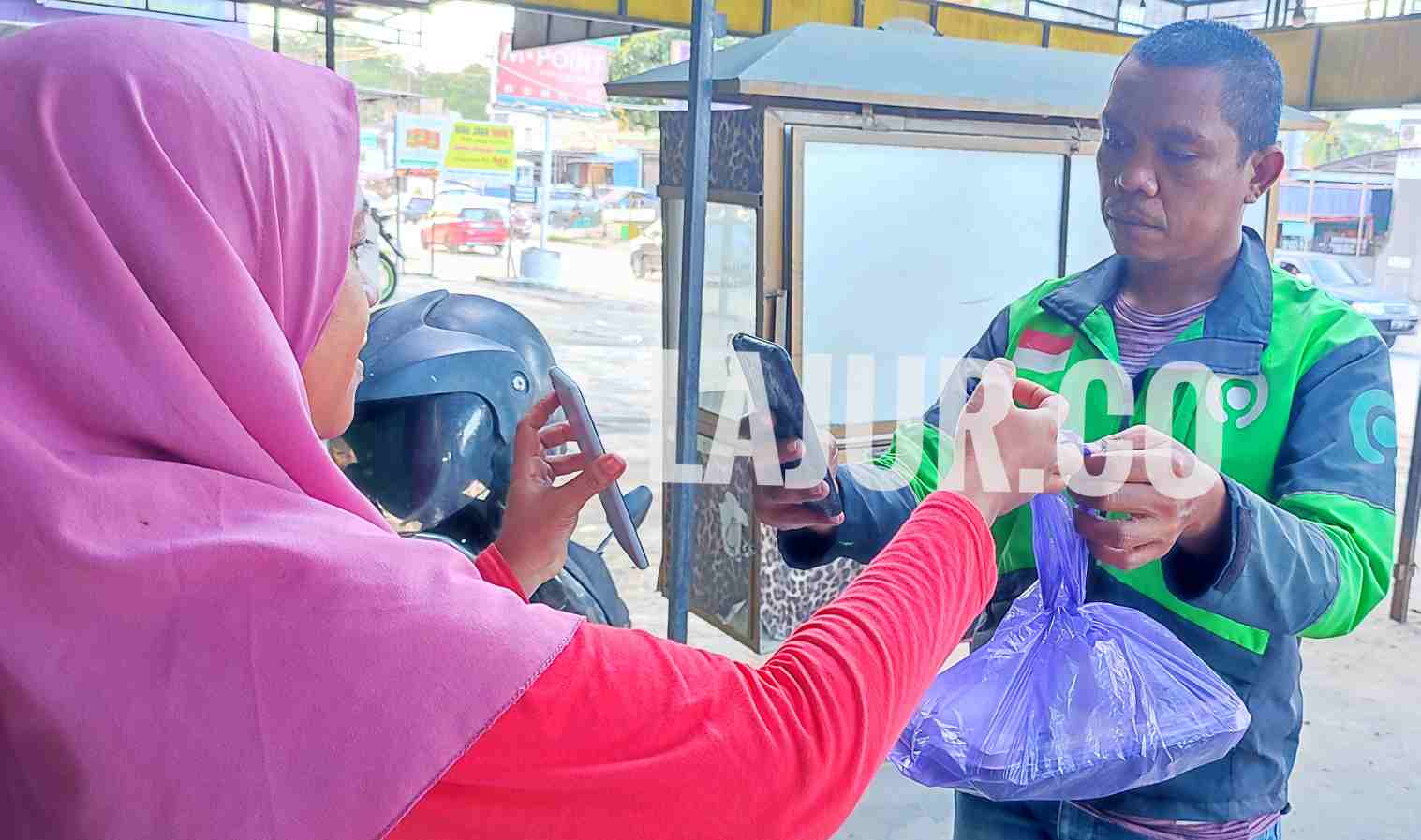Owner Nasi Tempong Tiga Cabe, Sutini Kasong menyerahkan paket Nasi Tempong yang diorder pelanggan menggunakan aplikasi pesan antar Gojek.